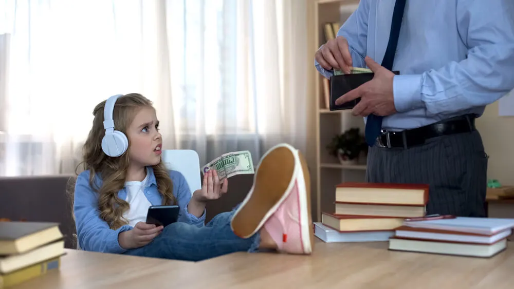 Busy father giving pocket money to little capricious daughter with headphones