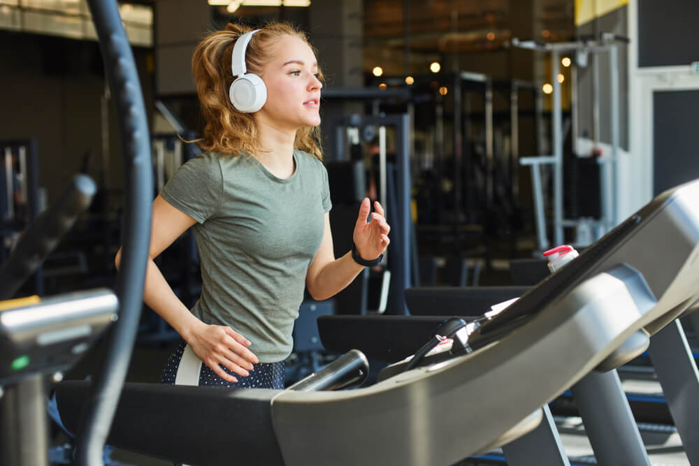 Girl in headphones running on the treadmill