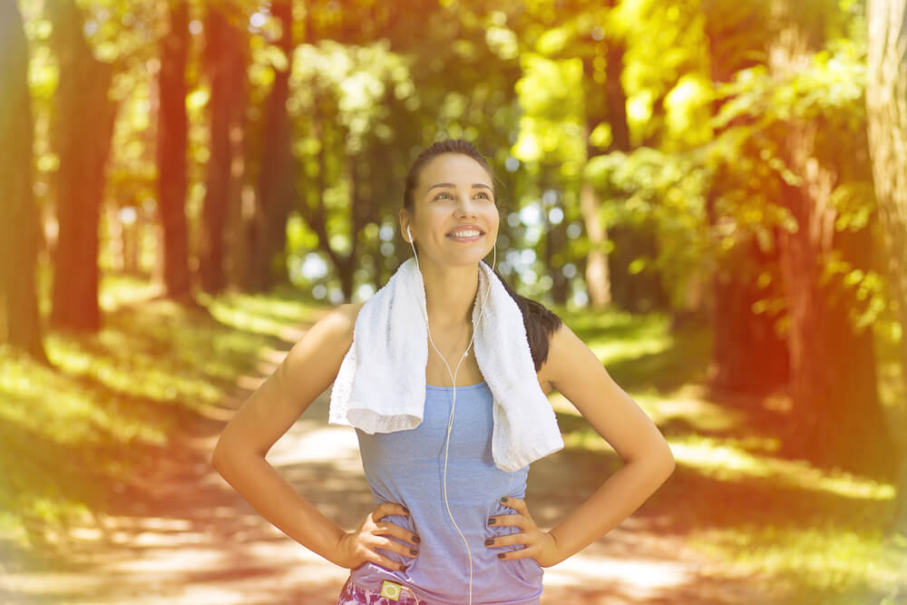 Portrait young attractive smiling fit woman with white towel resting after workout