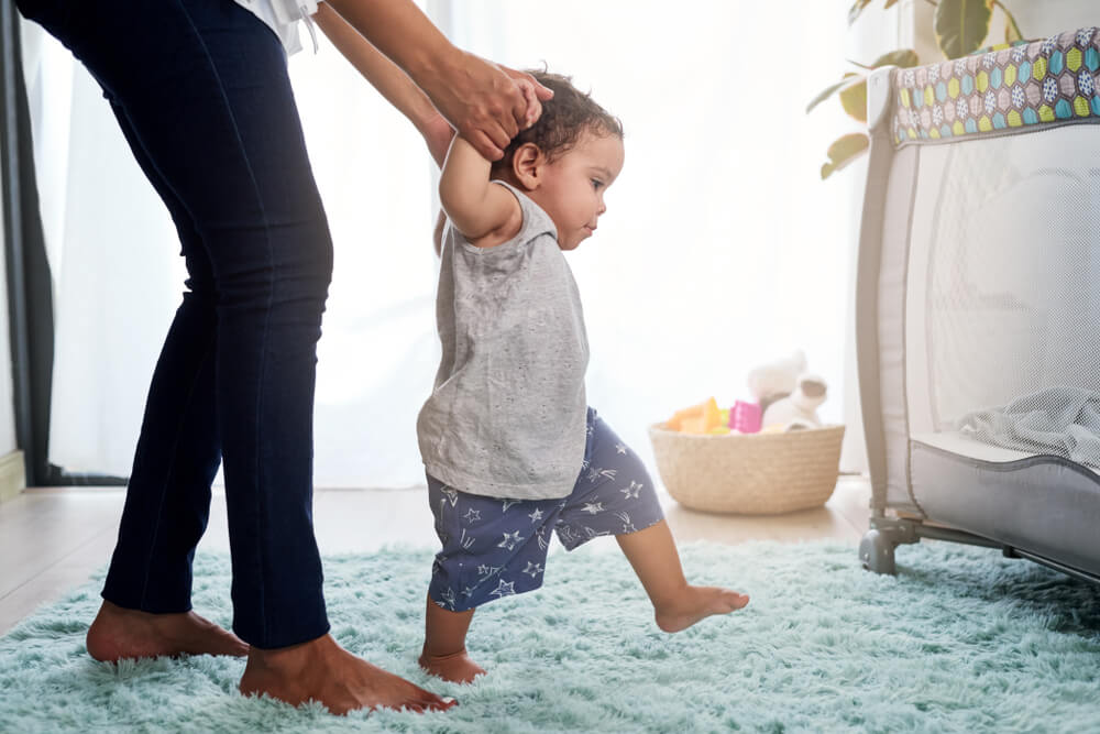 Baby's first steps holding mother's hands