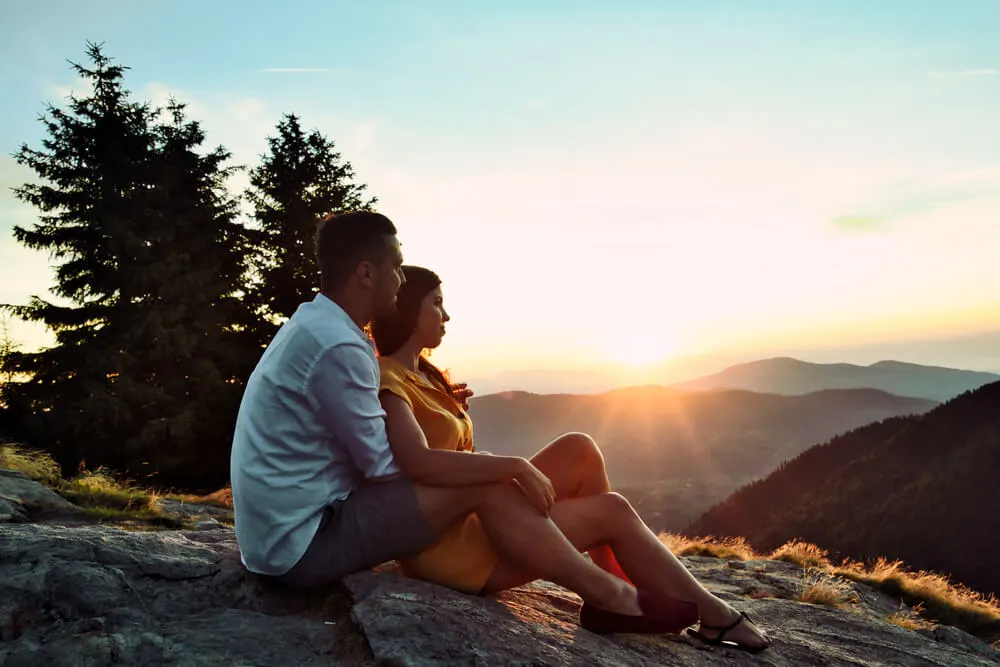 Happy couple hugging on the top of a mountain.