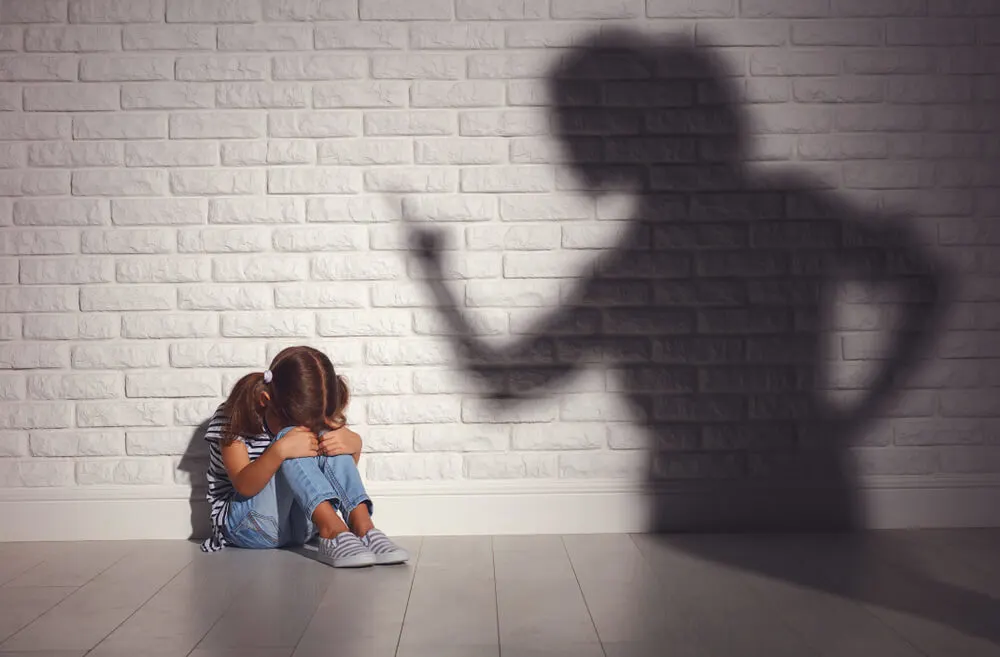 angry mother scolds frightened daughter sitting on floor