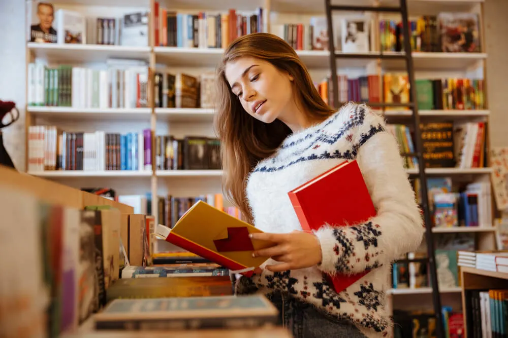 Beautiful brunette woman looking for a book in store