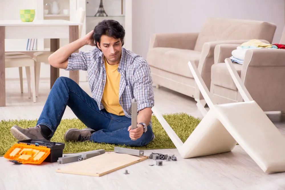 Young handsome man repairing chair at home