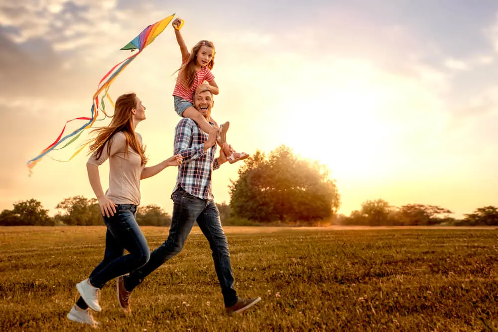 family running through field letting kite fly