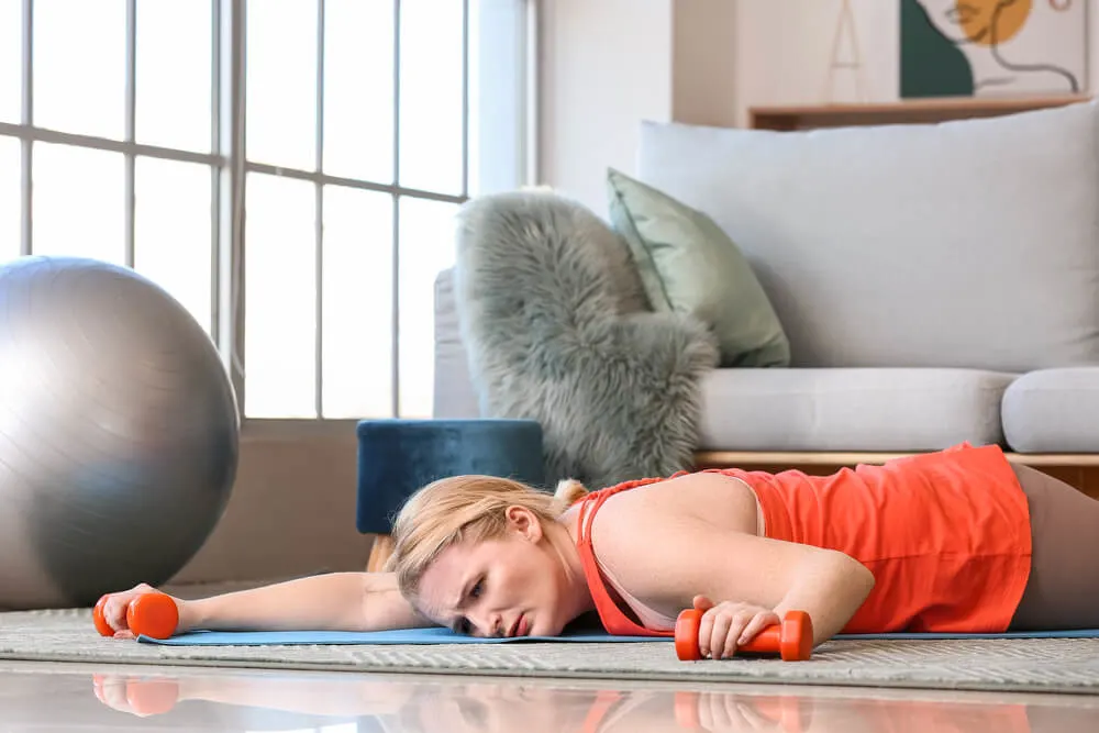 Exhausted woman with excess weight lying on floor after training at home