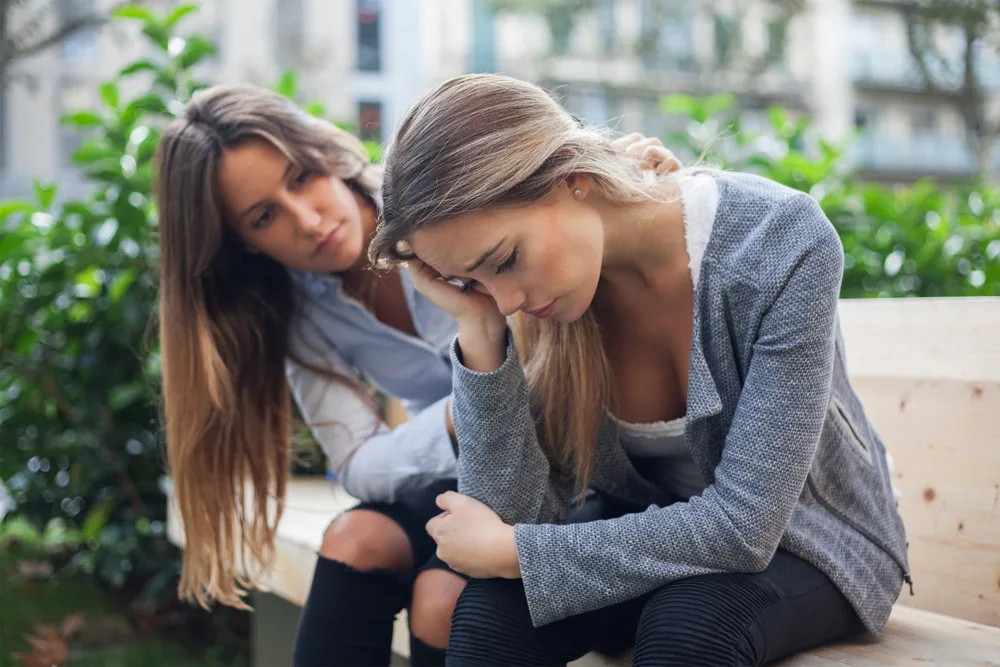 Woman comforting to a sad depressed friend who needs help