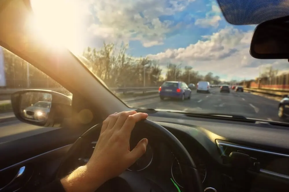 driver is driving his car in the city on a beautiful day