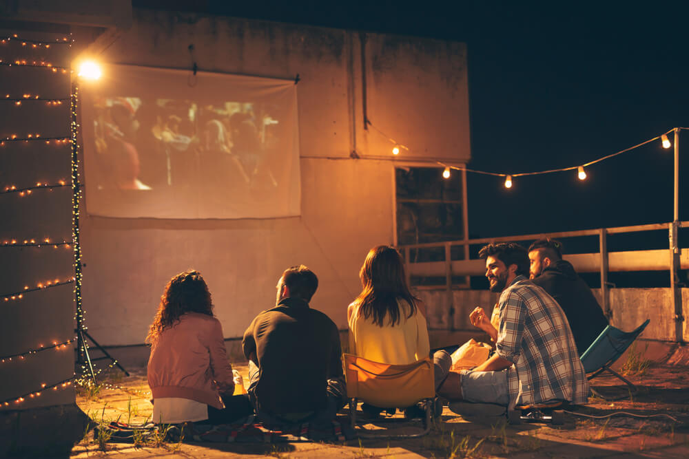 Group of young friends watching a movie on a building rooftop terrace