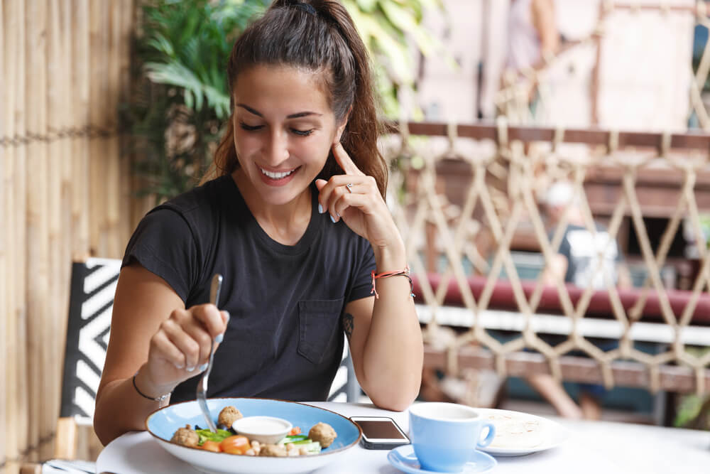 Girl drinking coffee, dining alone and smiling in a restaurant