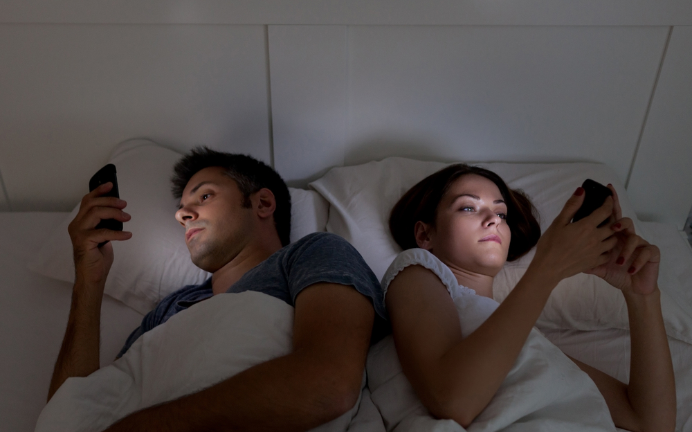 Couple with smartphones in their bed